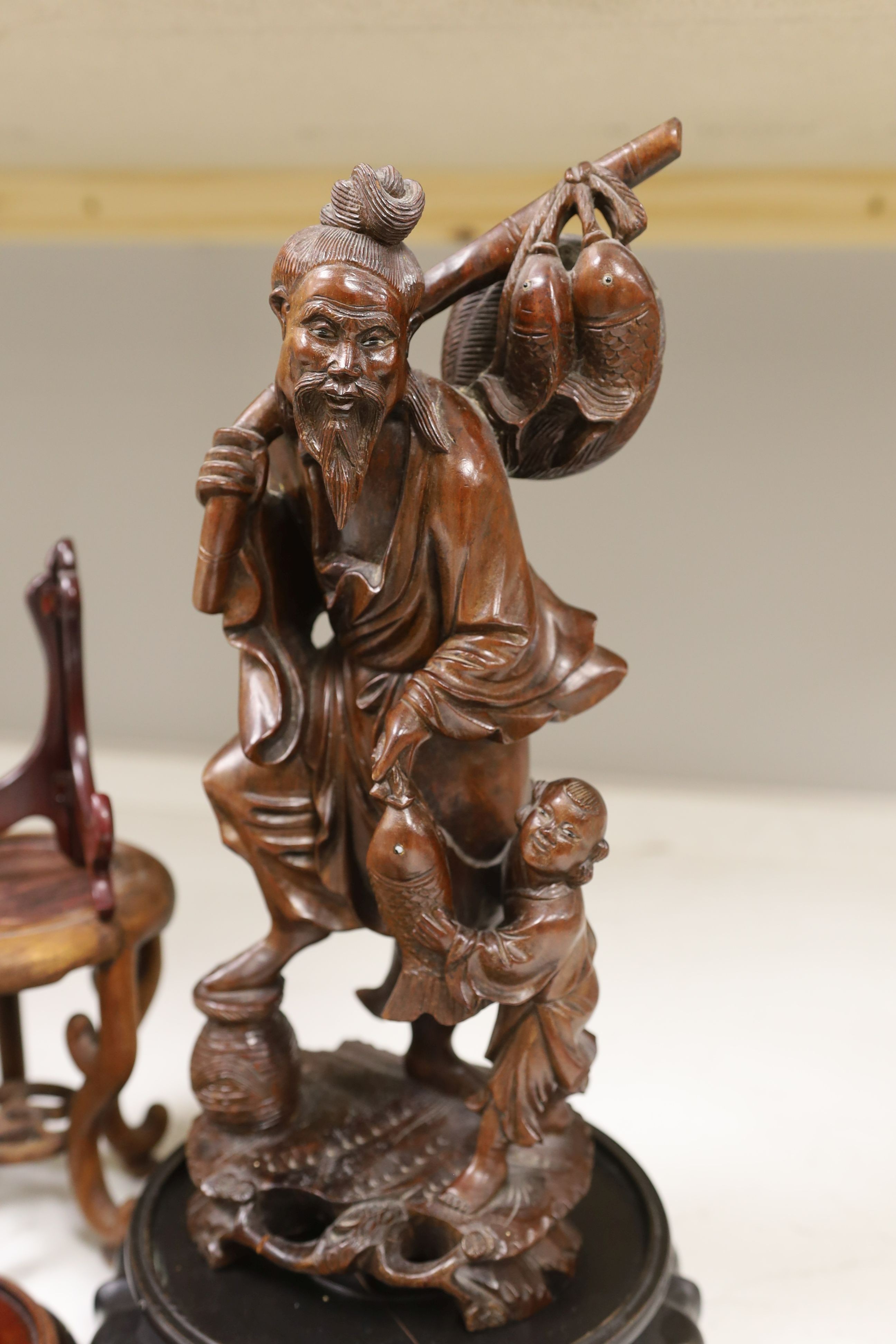 A Chinese hardwood figure of fisherman, 42cm tall including stand, and a quantity of wooden stands